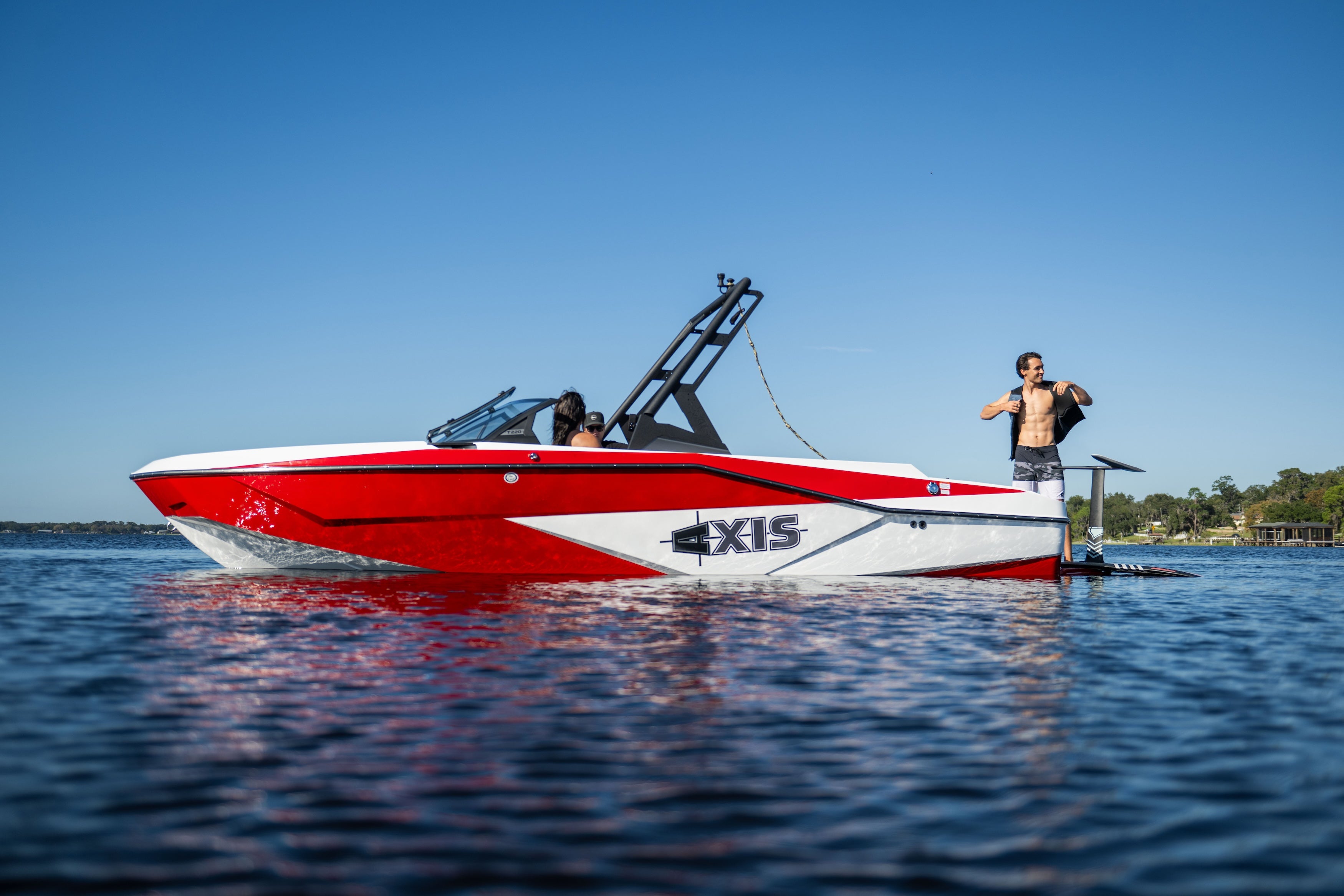 Axis AW20 Black Tower boat on the water with two people onboard, showcasing its sleek design and vibrant colors.