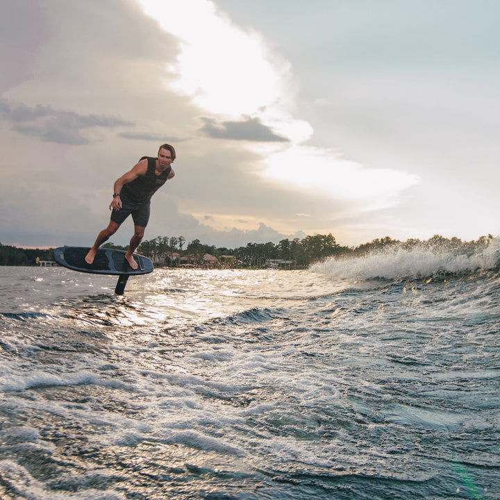 Man riding a high aspect foil board on water, showcasing dynamic movement and excitement in a boating environment.