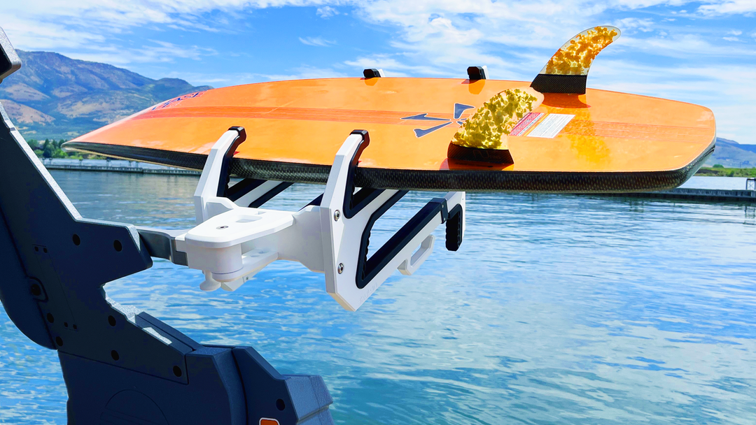 A surfboard secured on the Skylon Skylock Pro-4 locking rack mounted on a boat, with water and mountains in the background.