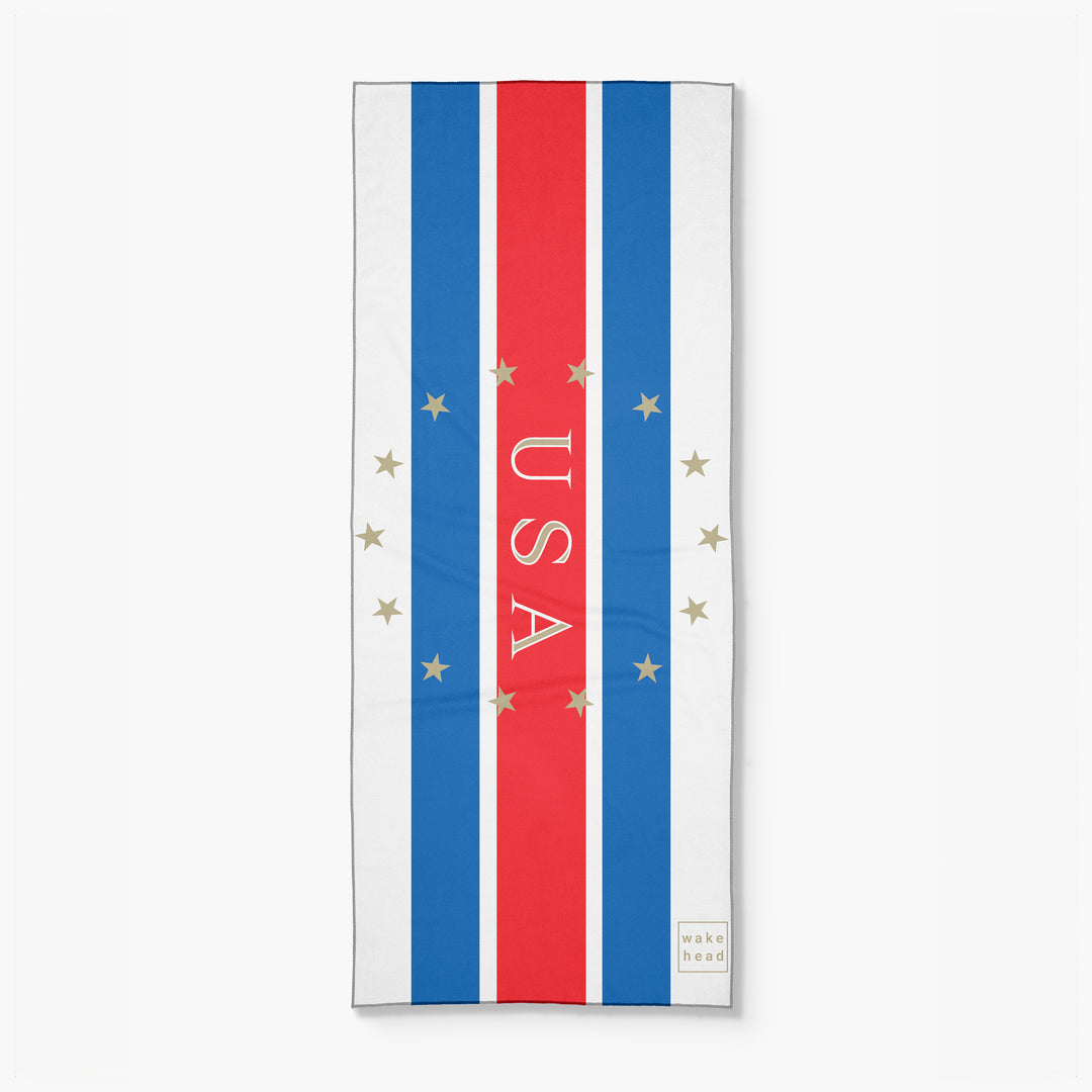 Stars and stripes lake towel with red, white, and blue vertical stripes, gold stars, and "USA" text in the center.
