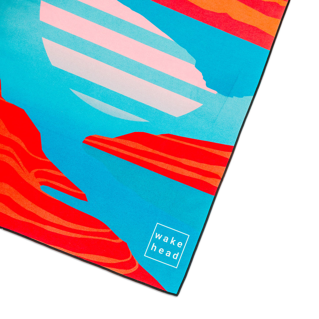 Colorful Powell Towel with abstract red, blue, and pink patterns, featuring the "Wake Head" logo in the corner.
