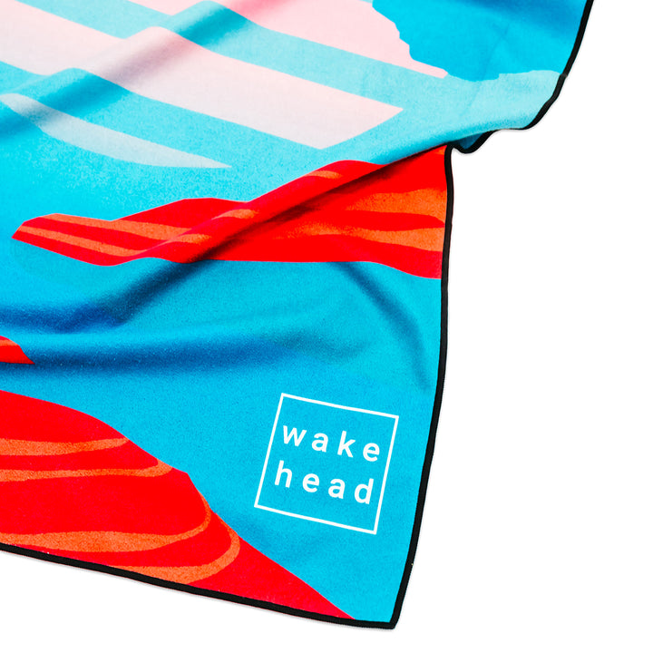 Colorful Powell Towel with a blue, red, and orange abstract design and "wake head" logo in white text.
