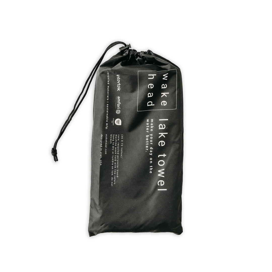 Black Powell Towel in a drawstring bag with white text, designed for quick drying and easy packing for travel or outdoor use.