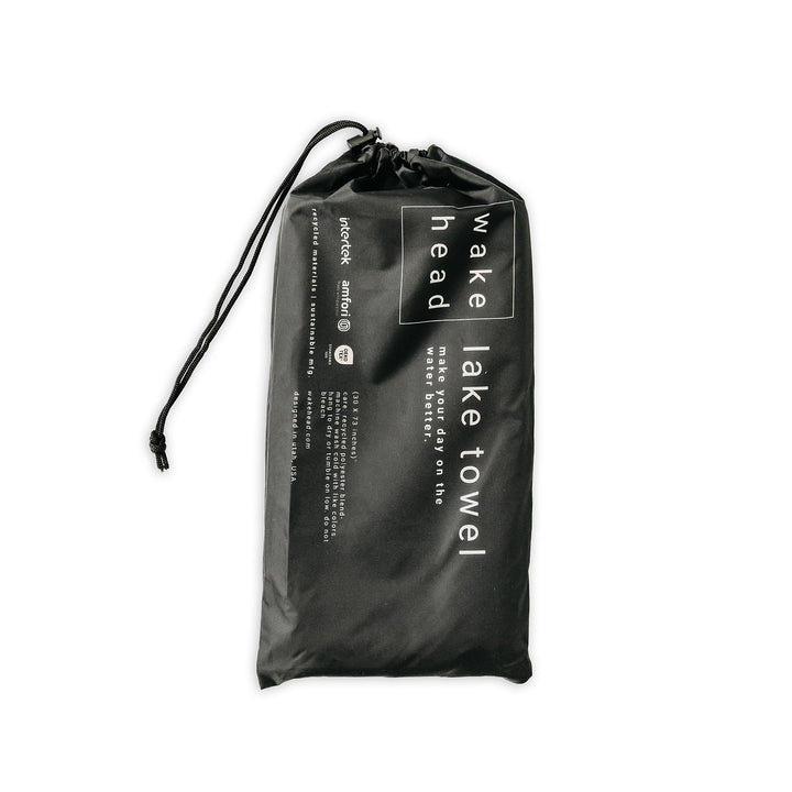 Black Powell Towel in a drawstring bag with white text, designed for quick drying and easy packing for travel or outdoor use.