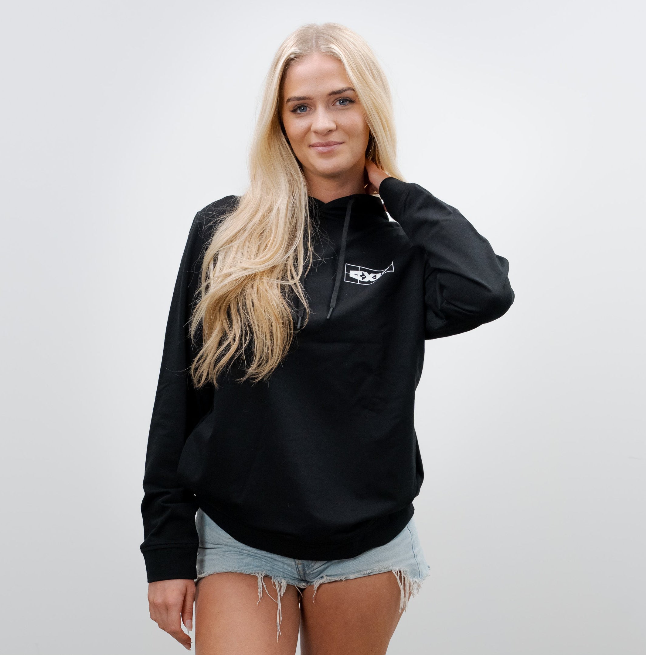 Young woman wearing a black AXIS hoodie, distressed denim shorts, and flip-flops, standing against a plain white background.