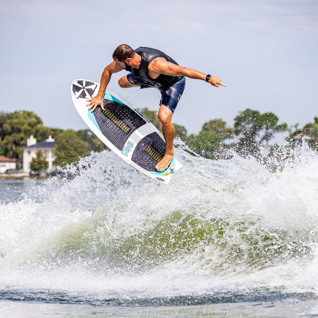 A surfer performs an aerial maneuver on the 2026 Phase Five Ahi board, showcasing its design and performance on water.