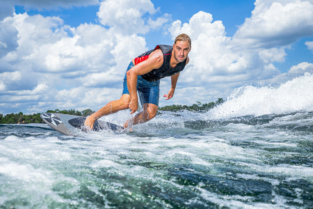A man surfing on a 2025 Phase 5 Ahi Stealth surfboard on choppy water under a partly cloudy sky.