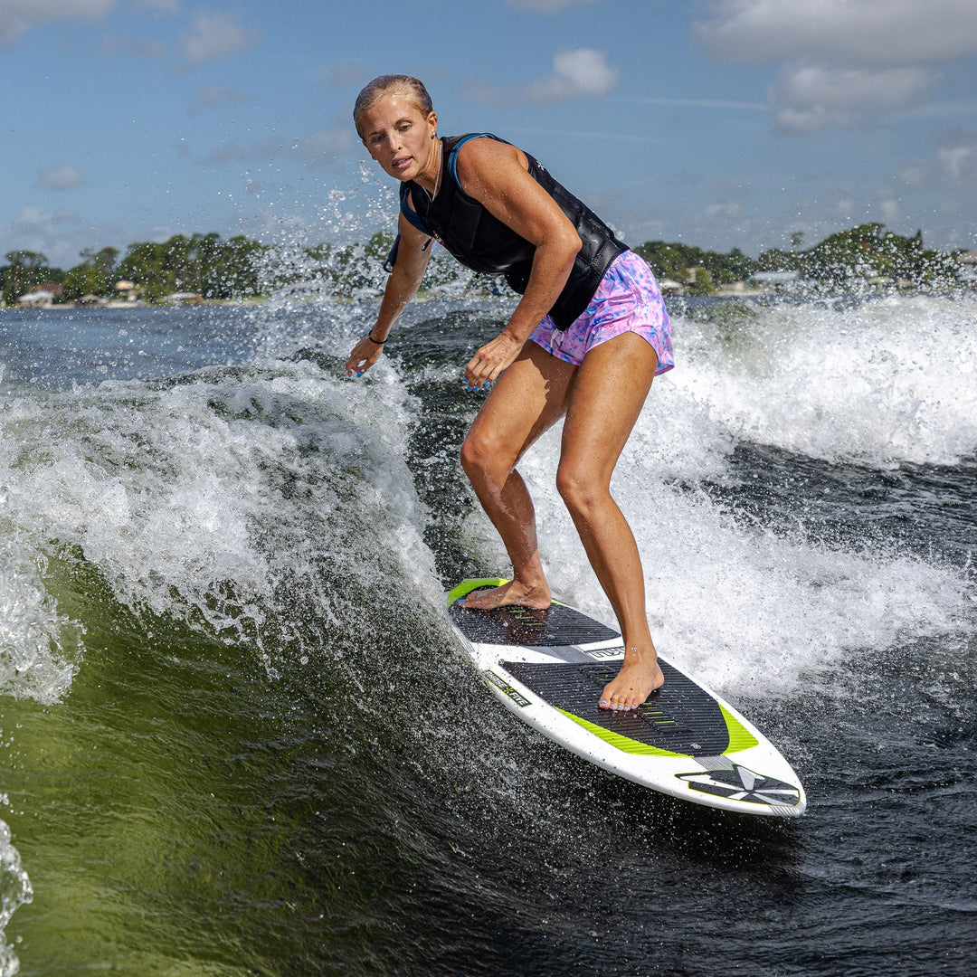 A woman surfing on a 2026 Phase Five Aku V2 board, riding a wave with determination and skill.