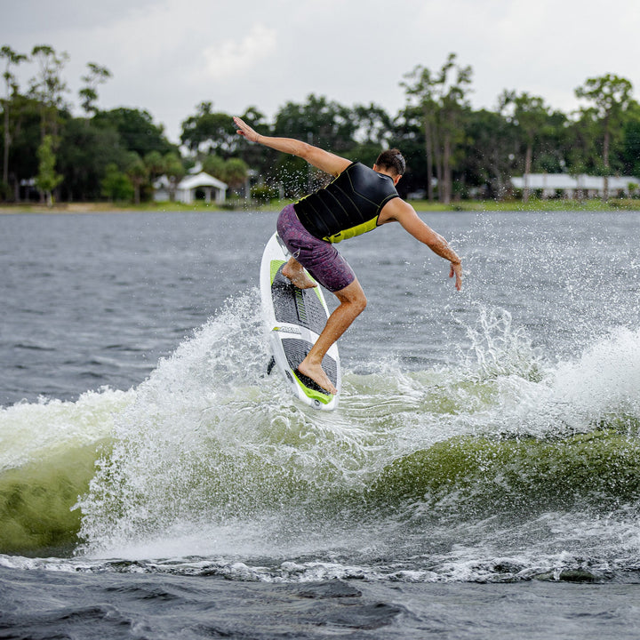 A person performing a trick on the 2026 Phase Five Aku V2 surfboard, creating a spray of water behind them.