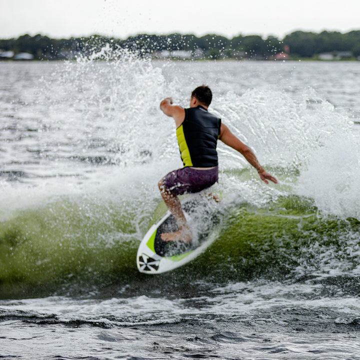 A person riding the 2026 Phase Five Aku V2 wakesurf board, carving through a wave on a lake.
