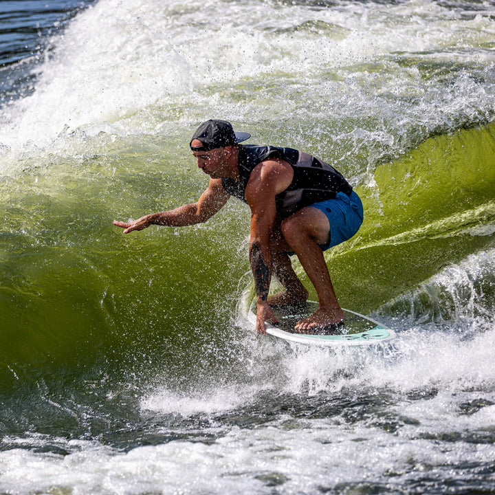 A surfer riding the 2026 Phase Five Avenger board on a wave, showcasing agility and skill in water sports.