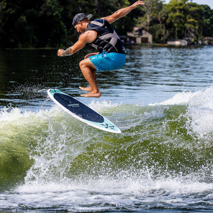 A person performing a jump on a 2026 Phase Five Avenger surfboard over a wave, showcasing water sports action.