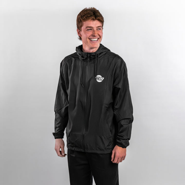 A smiling man wearing a black Offshore Jacket with a hood, showcasing a sleek design and logo on the chest.