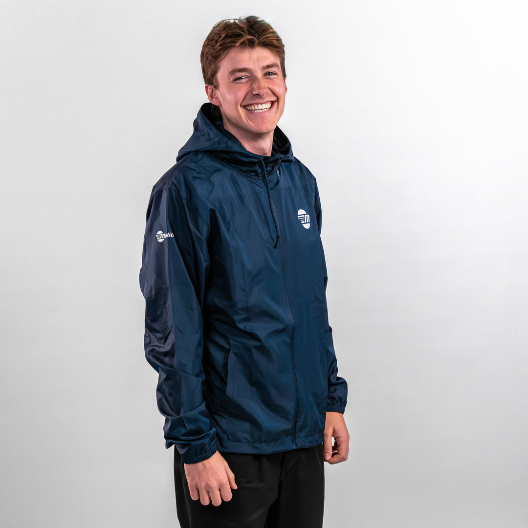 A young man smiles while wearing a navy offshore jacket with a hood, showcasing its lightweight design and comfort.