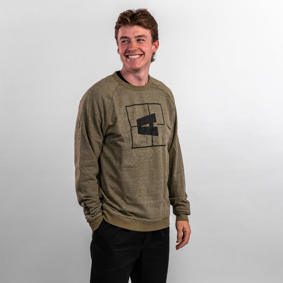 Man wearing an olive green Axis crewneck sweatshirt with a black logo design, smiling against a neutral background.