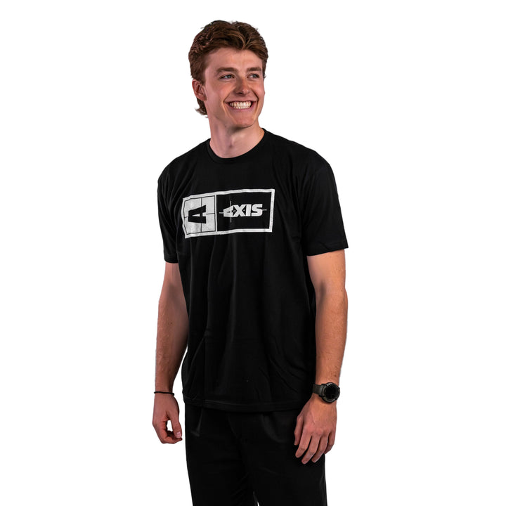 A young man wearing a black Axis Statement Tee, smiling and standing confidently against a neutral background.