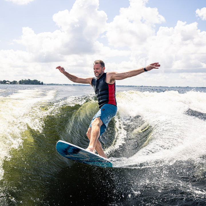 A person surfing on a 2026 Phase Five Diamond CL board, riding a wave with a sunny sky in the background.