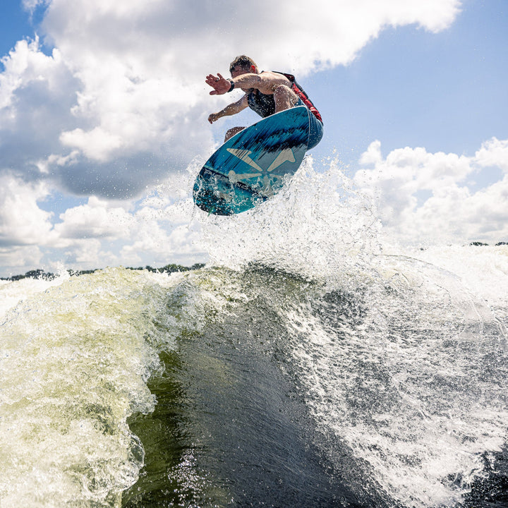 A person performing a jump on a wakeboard over a wave, showcasing the 2026 Phase Five Diamond CL design.