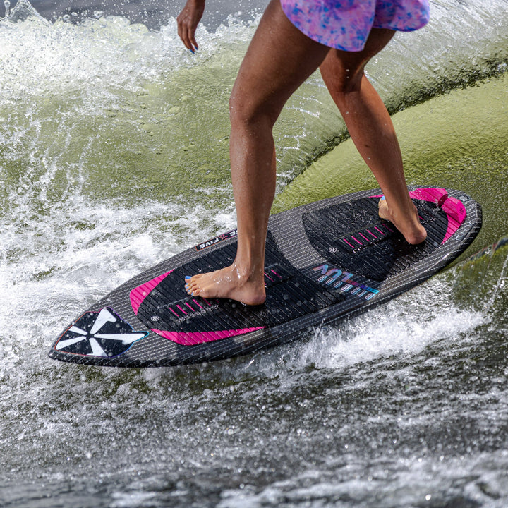 A person rides the 2026 Phase Five Diamond Luv surfboard on a wave, showcasing its sleek design and vibrant colors.