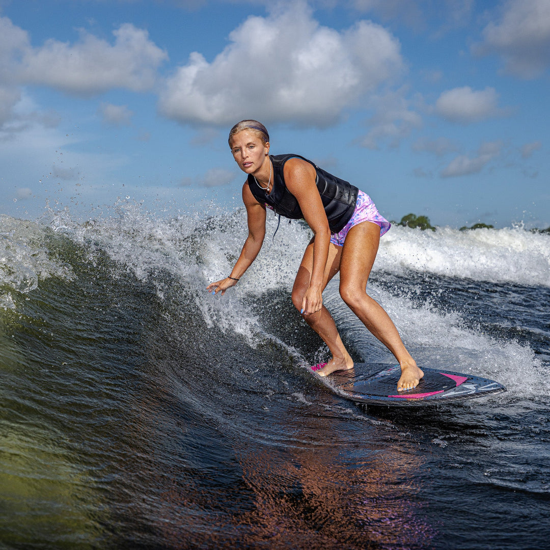 A woman rides a wave on the 2026 Phase Five Diamond Luv surfboard, showcasing her skills in a dynamic water setting.
