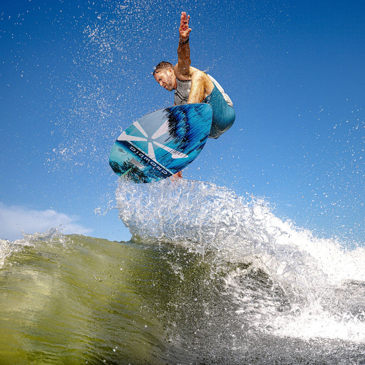 A surfer performs a jump on a 2026 Phase Five Diamond Turbo board, showcasing dynamic movement over ocean waves.