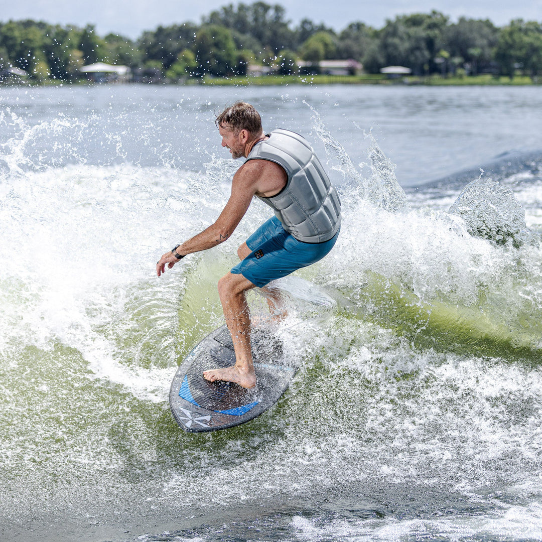A person riding the 2026 Phase Five Diamond Turbo surfboard, creating a spray of water while surfing on a lake.