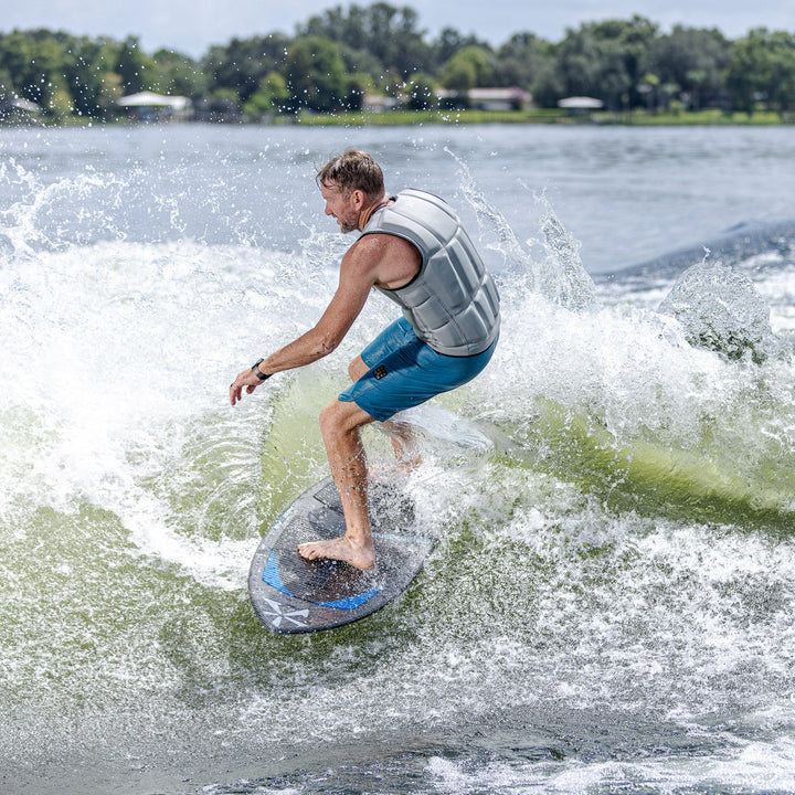 A person riding the 2026 Phase Five Diamond Turbo surfboard, creating a spray of water while surfing on a lake.