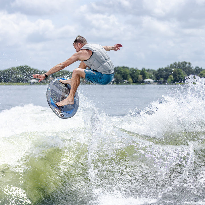 A man performs a jump on a 2026 Phase Five Diamond Turbo surfboard, creating a splash in the water.