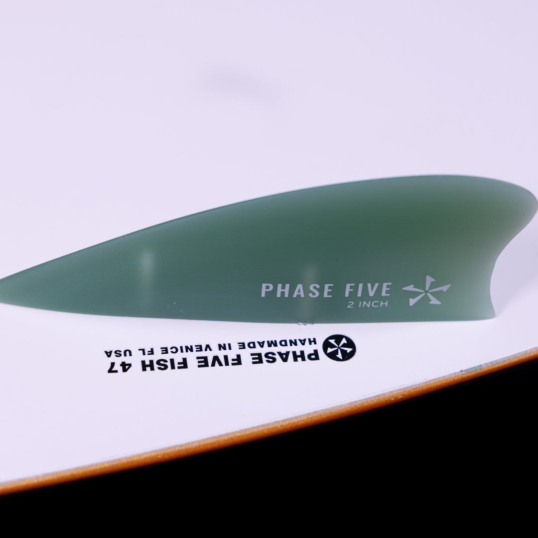 Close-up of the fin on a 2025 Phase 5 Fish skimboard, showcasing its sleek design and brand details.