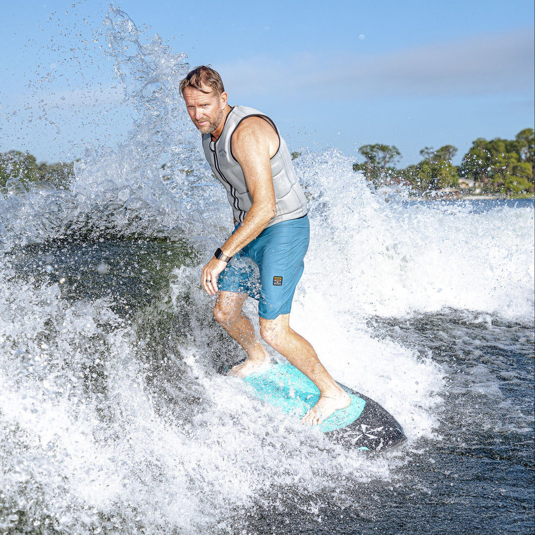 A man rides the 2026 Phase Five Hammerhead V3 surfboard, creating a splash on the water while enjoying a day of wake surfing.