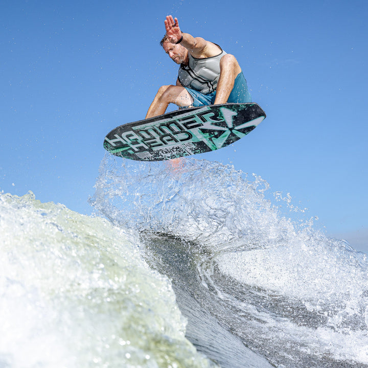 A rider performs a jump on the 2026 Phase Five Hammerhead V3 surfboard, showcasing dynamic movement on a wave.