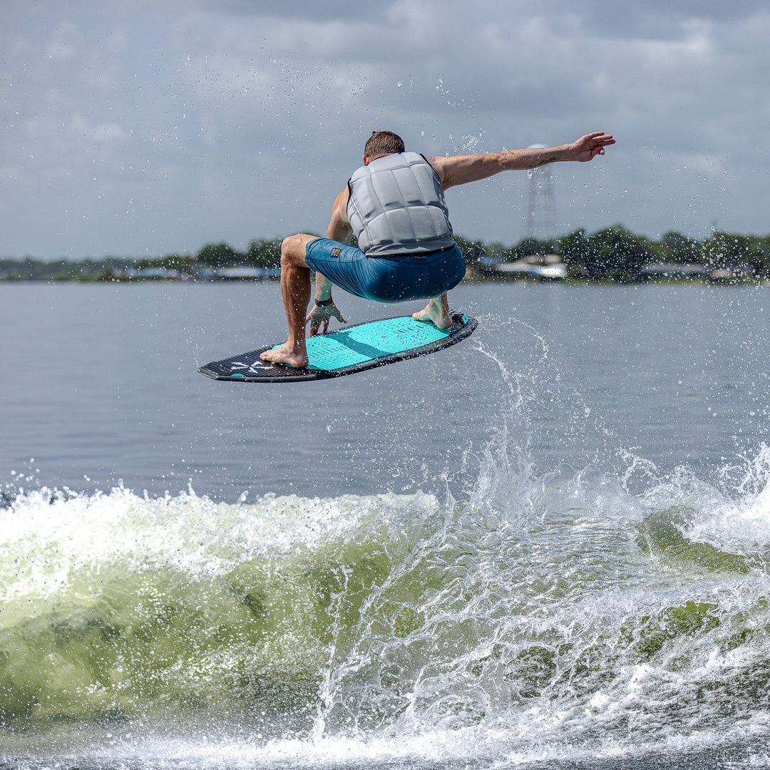 A person performing a jump on a wakeboard over a wave, showcasing the 2026 Phase Five Hammerhead V3 in action.