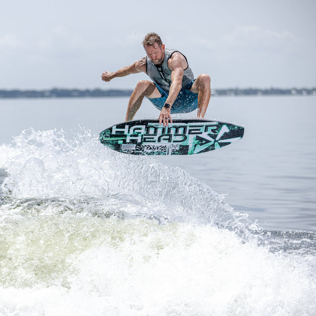 A person performs a jump on a 2026 Phase Five Hammerhead V3 surfboard over a wave, showcasing dynamic water sports action.