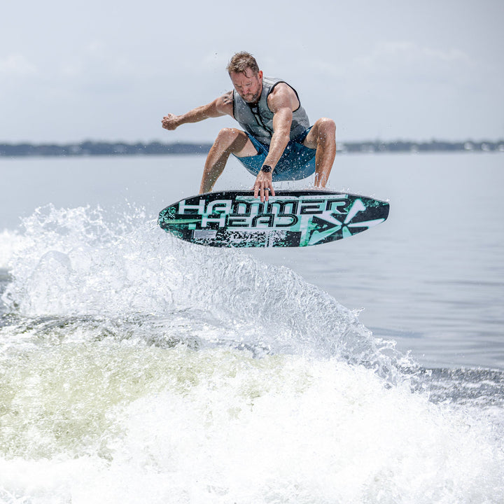 A person performs a jump on a 2026 Phase Five Hammerhead V3 surfboard over a wave, showcasing dynamic water sports action.