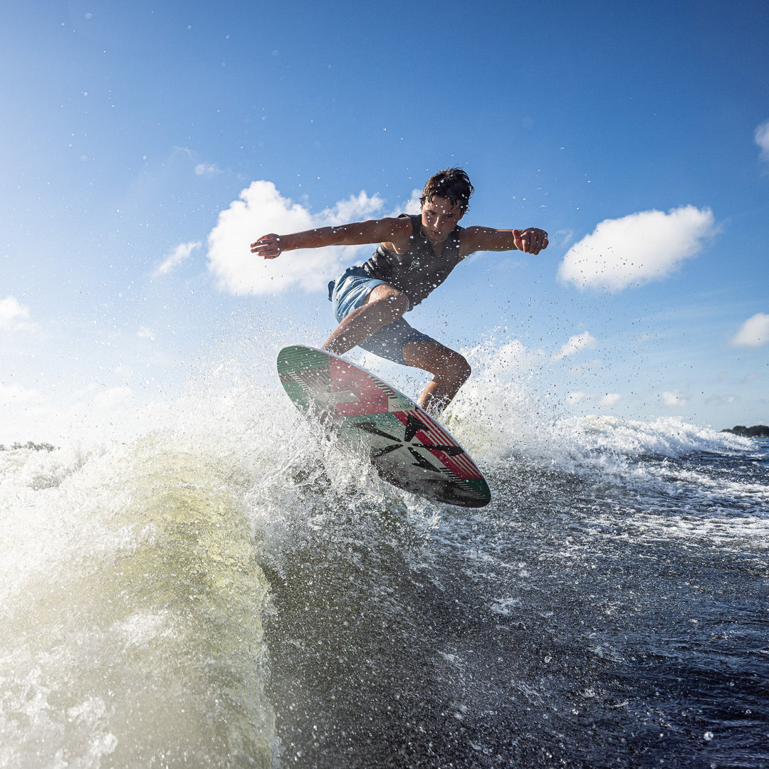 A person performing a jump on a wakeboard over a wave, showcasing the excitement of water sports.