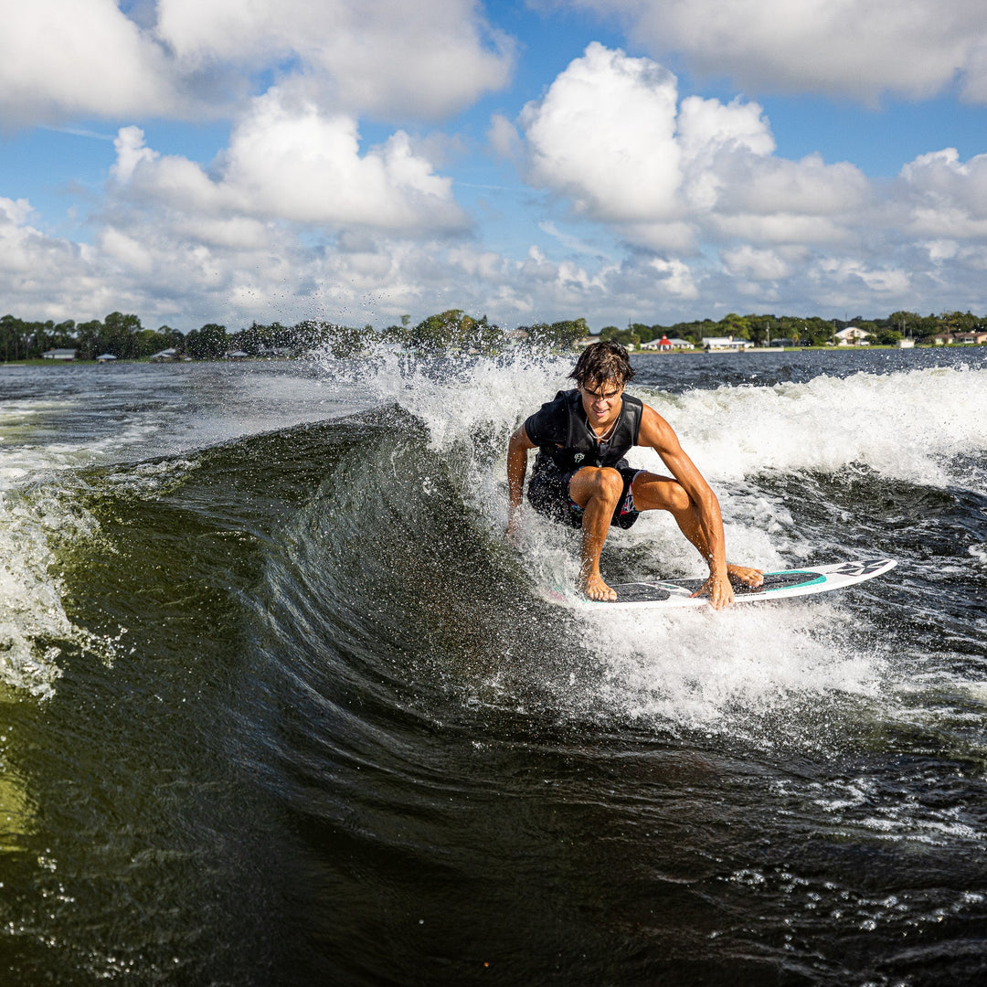 A person riding the 2026 Phase Five Key CL surfboard on a wave, showcasing dynamic movement and water spray.