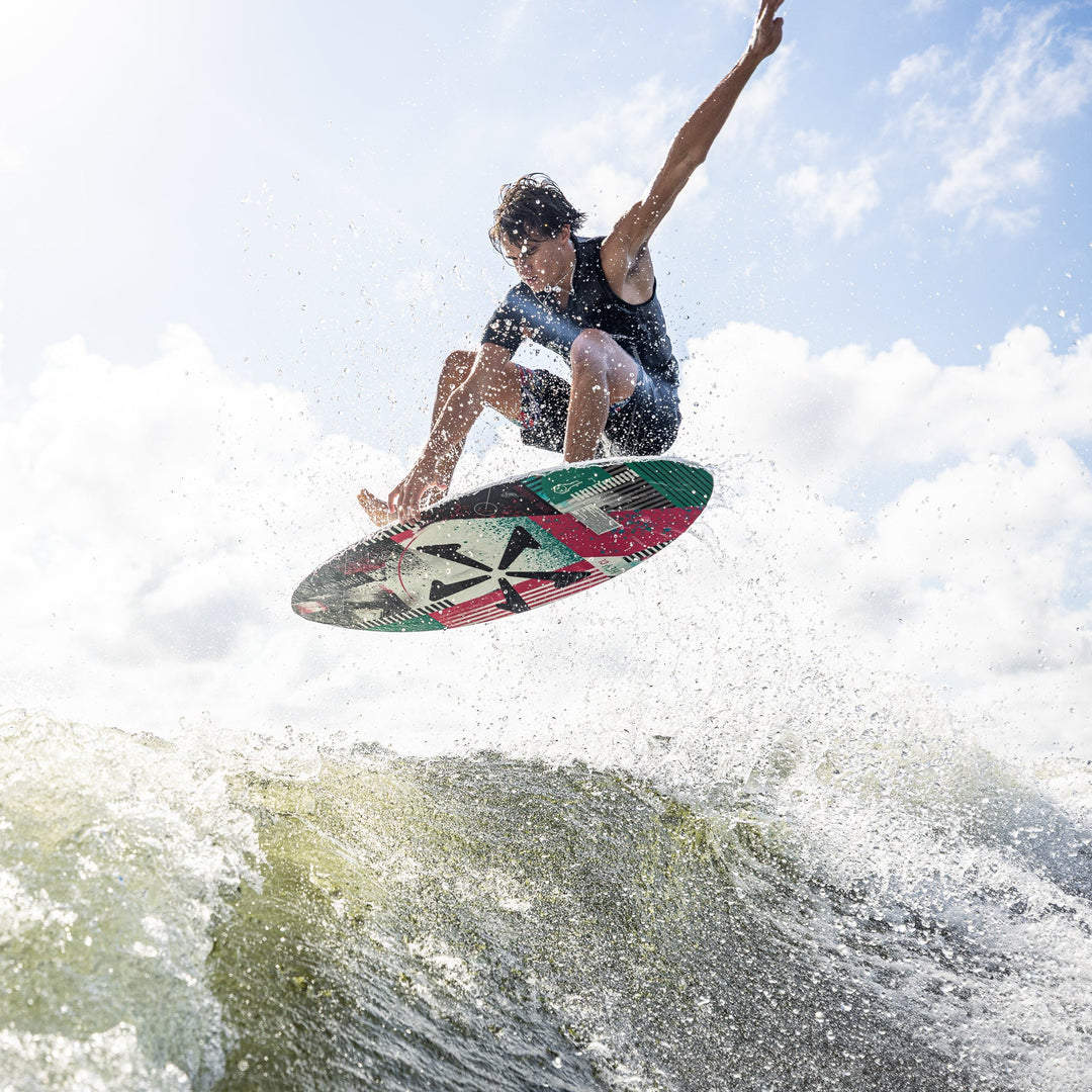 A young man performs a jump on a wakeboard over a wave, showcasing the 2026 Phase Five Key CL design.