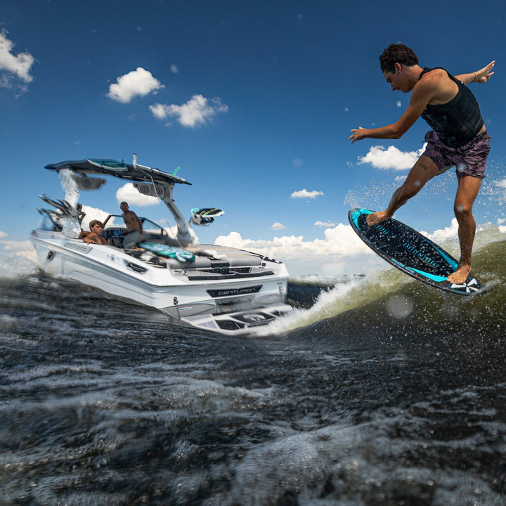 A person surfing on a wakeboard behind a boat on a sunny day, showcasing the excitement of water sports.