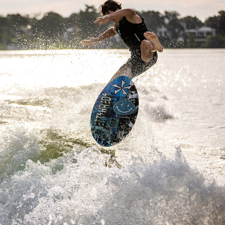 A person performs a jump on a 2026 Phase Five Key Jett Shreds surfboard, creating splashes on the water.