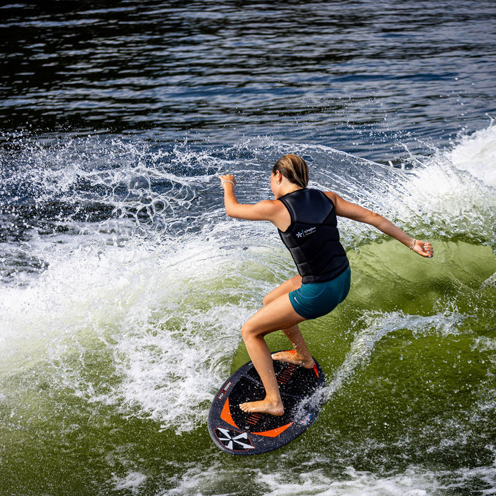 A person surfing on a wakeboard, showcasing the 2026 Phase Five Key Stewart Pro, with water splashing around.