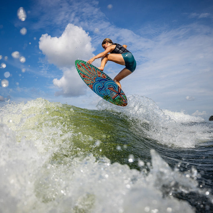 A person performs a jump on a colorful wake surfboard over a wave, showcasing the 2026 Phase Five Key Stewart Pro in action.