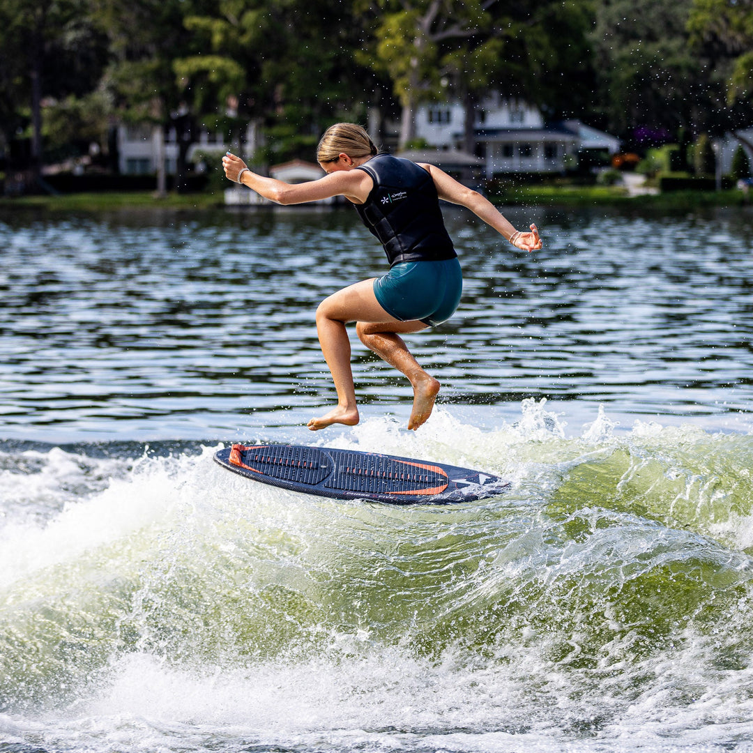 A person performs a jump on a wake surfboard over a wave, showcasing the 2026 Phase Five Key Stewart Pro in action.
