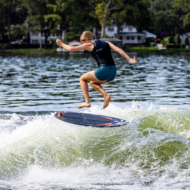 A person performs a jump on a wake surfboard over a wave, showcasing the 2026 Phase Five Key Stewart Pro in action.