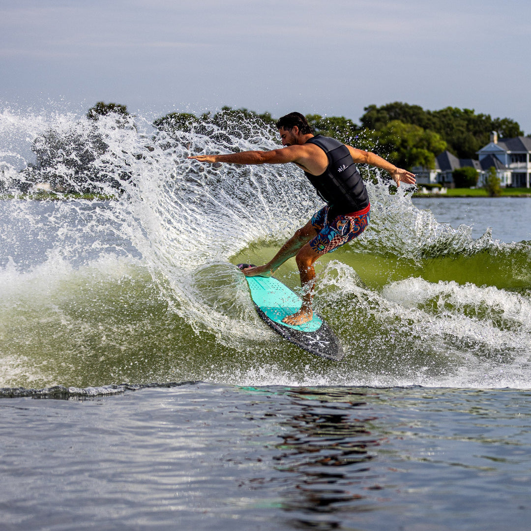 A person riding the 2026 Phase Five Key V2 wakesurf board, carving through a wave on a lake.