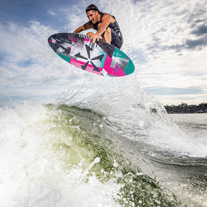 A rider performs a jump on the 2026 Phase Five Key V2 surfboard above a wave, showcasing dynamic movement and style.