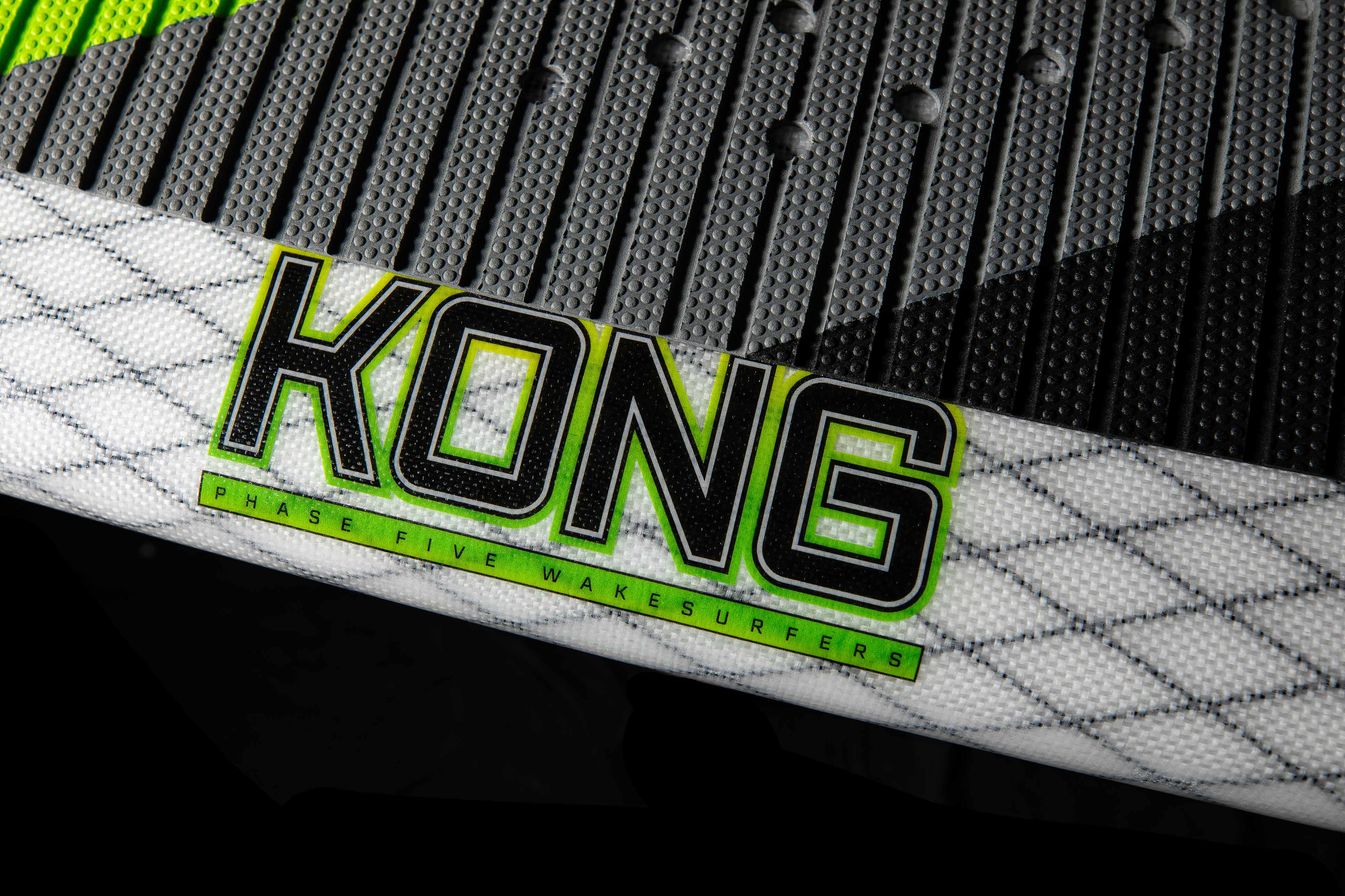 Close-up of the 2025 Phase 5 Kong surfboard with bold "KONG" logo and textured grip pad, featuring neon green accents.