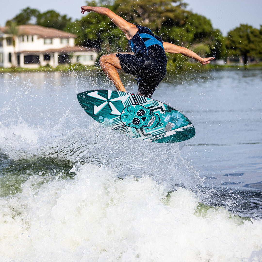 A person performs a jump on a 2026 Phase Five Matrix Pro wake surfboard over a wave, showcasing dynamic water sports action.