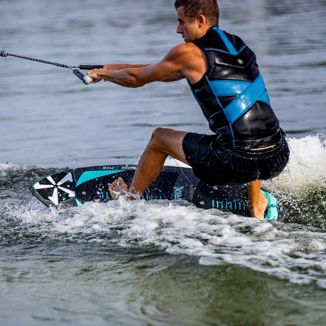 A person riding the 2026 Phase Five Matrix Pro wakesurf board, carving through water with a rope in hand.