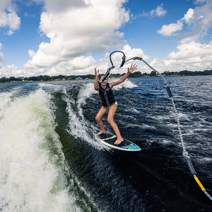 A young person enjoys surfing on a 2026 Phase Five Minnow behind a boat, showcasing skill and excitement on the water.
