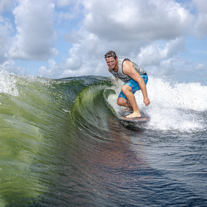 A surfer riding a wave on a 2026 Phase Five Model X, showcasing performance and style on the water.